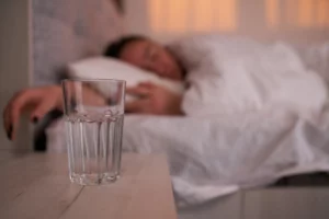 empty water glass by sleeping person in bed